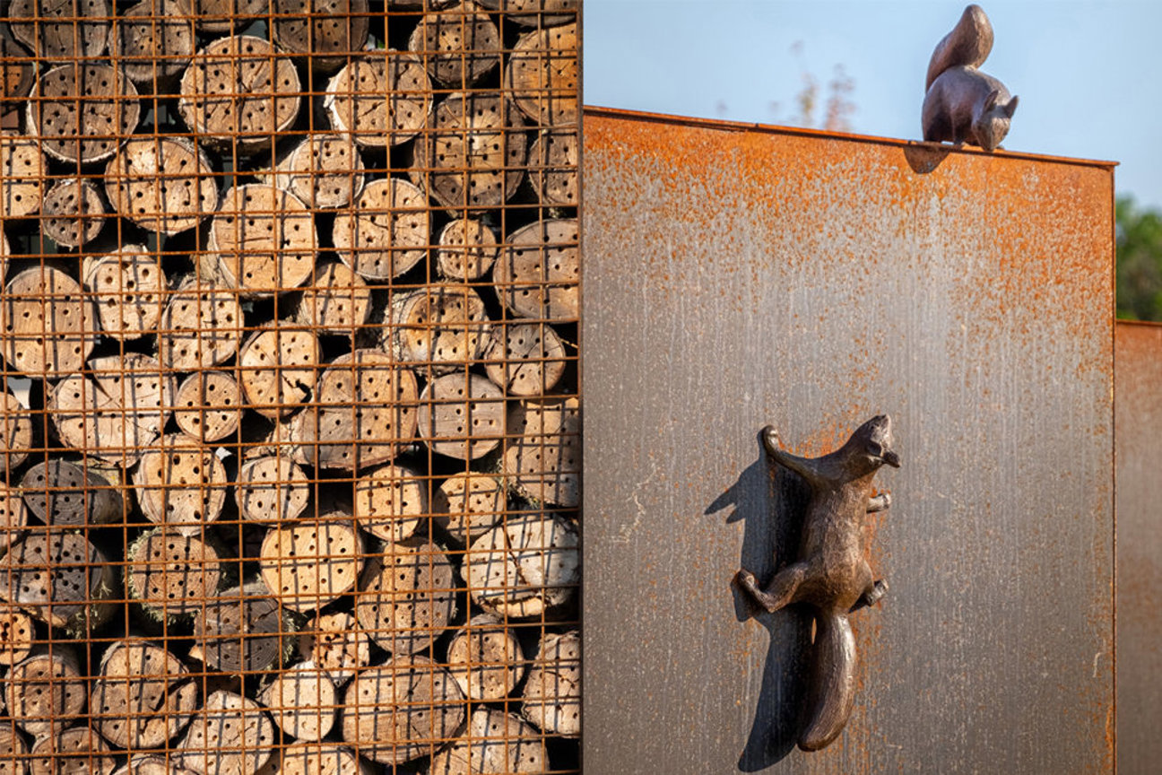 Metallskulpturer av ekorrar på rostig panel och trärullar i nät.