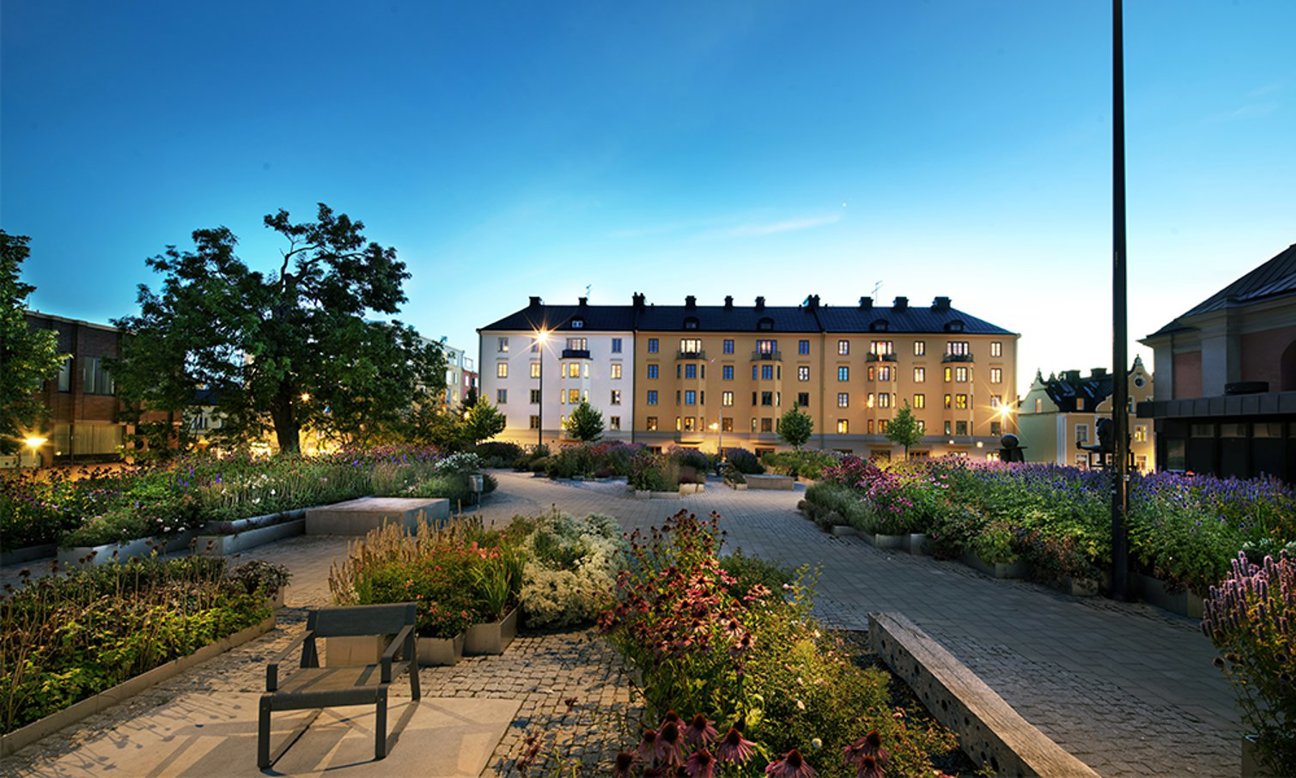 En byggnad med trädgård och blommor vid kvällstid.